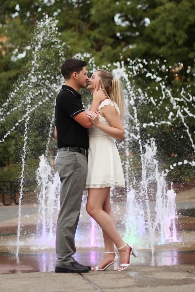 couple kissing in front of water fountain