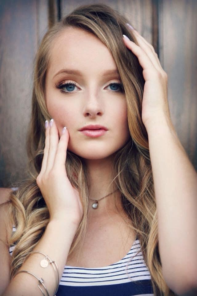 young women framing her face with her hands and a serious expression