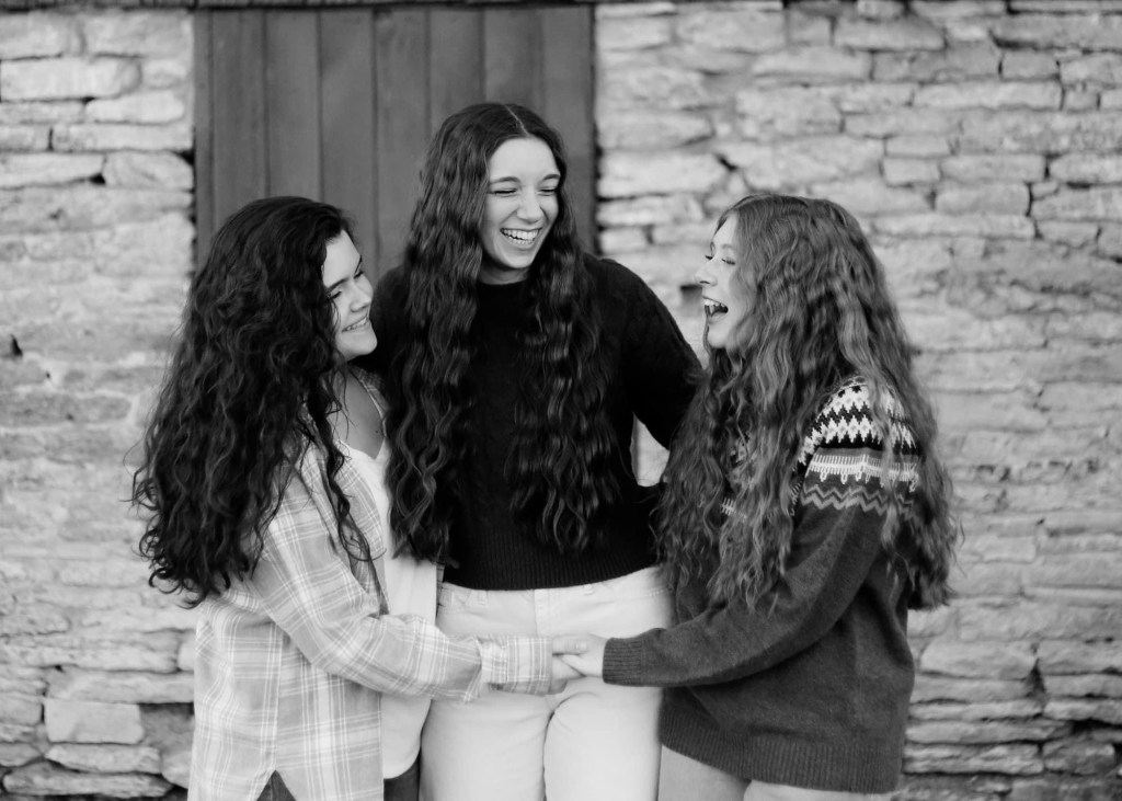 three sisters in black and white photo laughing and looking at each other