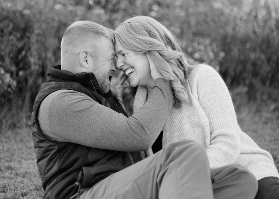 black and white photo of man and women laughing and man holding woman's face. 