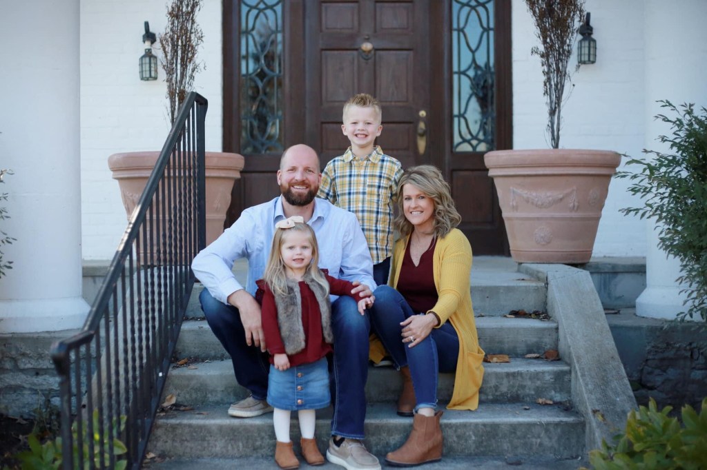 man and women with their two kids one boy, one girl, smiling on steps in front of a large door