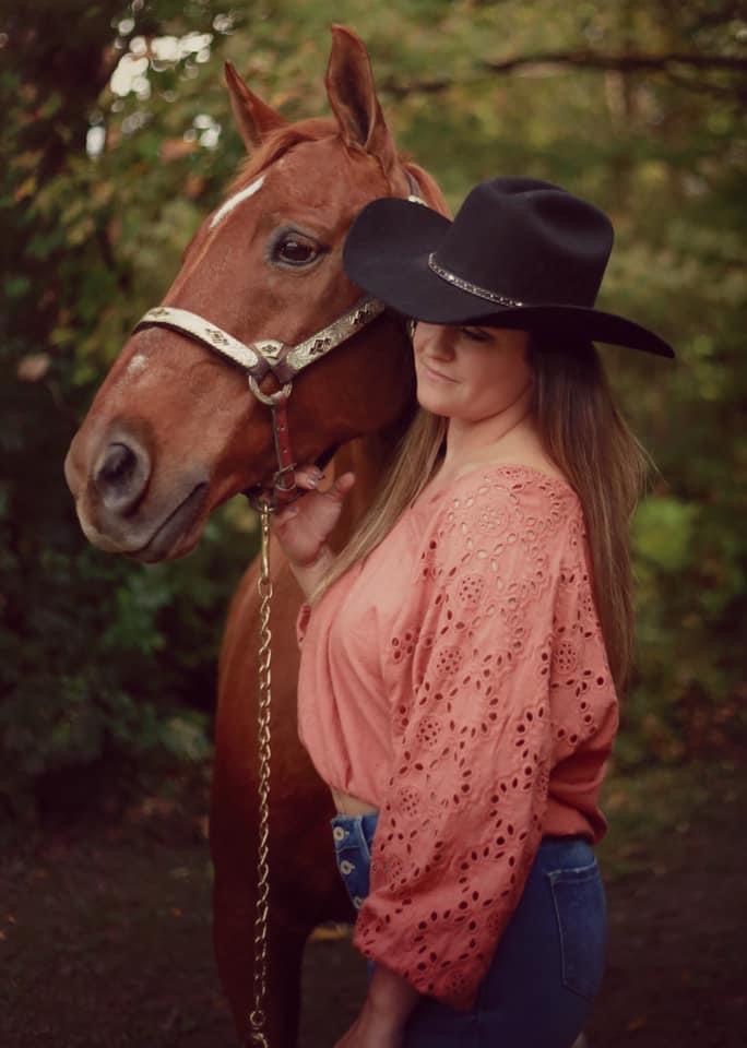 young women smiling with a brown horse 